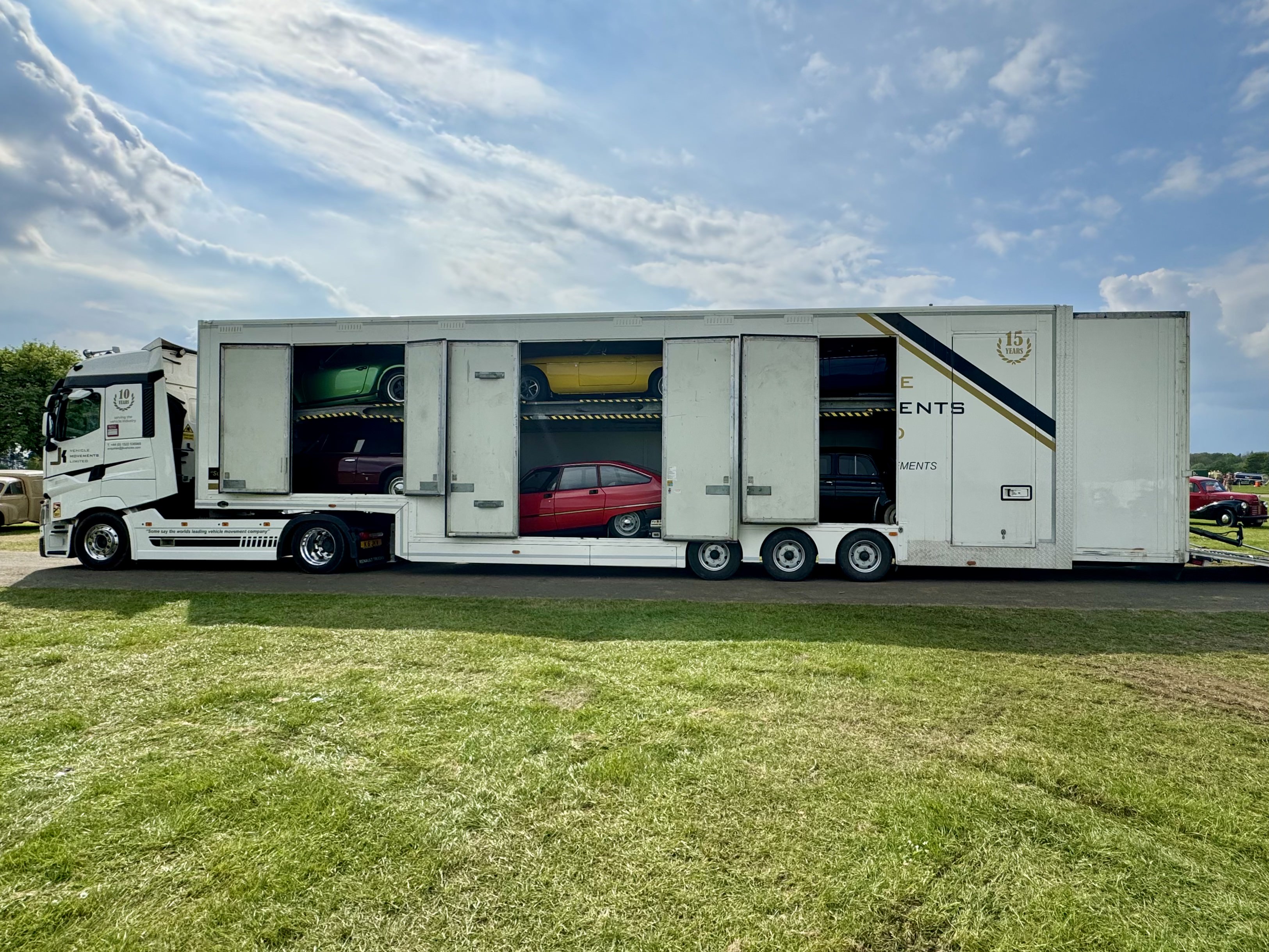 JK Vehicles transporter with open doors showing loaded classic cars